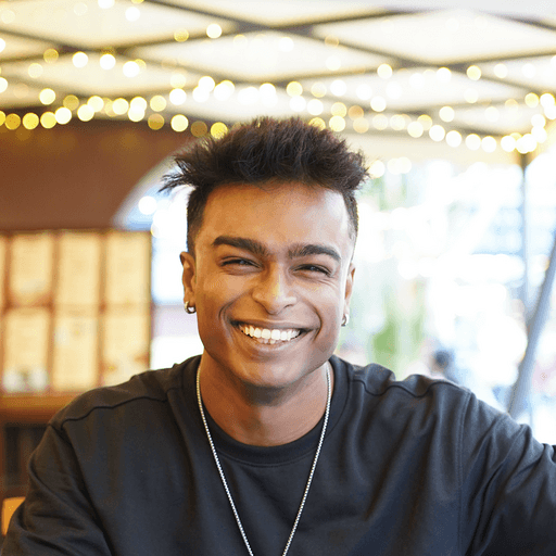Allan Jeo Joseph, smiling, in a cafe strung with fairy lights
